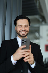 Wall Mural - A man in a suit is smiling while looking at his cell phone. He is wearing a tie and he is in a professional setting