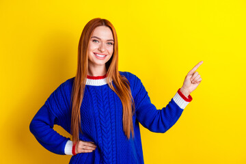 Wall Mural - Photo portrait of attractive young woman point empty space dressed stylish blue knitwear clothes isolated on yellow color background