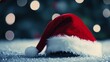 © grape_vein - A festive red and white Santa hat resting on a sparkling surface with blurred holiday lights