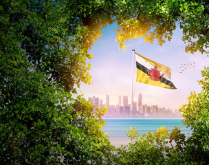 Brunei flag waving with modern skyline. A flag blow behind the tree leafs. Brunei national flag for independence day.