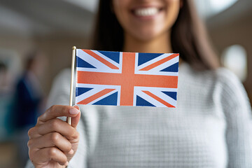 a happy female immigrant holding a small British flag on the day of her naturalization