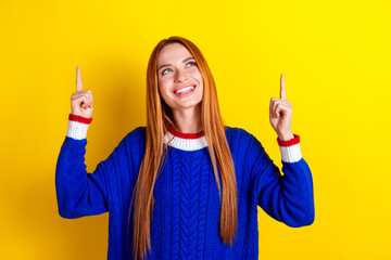 Wall Mural - Photo portrait of attractive young girl point look up empty space dressed stylish blue knitwear clothes isolated on yellow color background