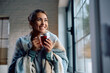 © Drazen - Happy woman wrapped in  blanket enjoying in cup of warm tea at home.