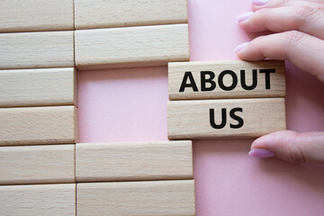 Wall Mural - About us symbol. Wooden blocks with words About us. Beautiful pink background. Businessman hand. Business and About us concept. Copy space.