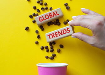 Global Trends symbol. Concept word Global Trends on wooden blocks. Beautiful yellow background with coffee cup. Businessman hand. Business and Global Trends concept. Copy space