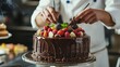 © Faxri - In the kitchen, a pastry chef is creating a cake with chocolate, fruit, and candy.Chocolate cake decoration, cooking classes, baking, and the concepts of food and people are all done by confectioners.