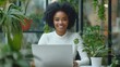 © ifoto - A black businesswoman sitting at an office desk, smiling and typing on her laptop computer in front of the screen