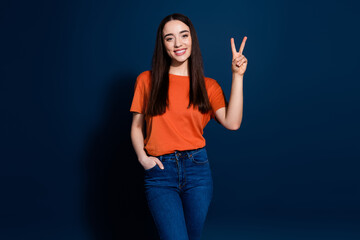 Wall Mural - Photo of adorable cheerful glad woman wear trendy orange clothes v-sign isolated on dark blue color background