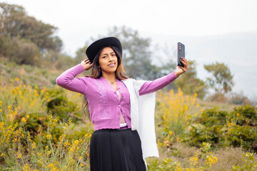 Atractiva joven campesina  con sombrero responde a videollamadas al aire libre, chica inteligente se comunica con entusiasmo en conferencia en línea al aire libre,campesina hablando de grabar 