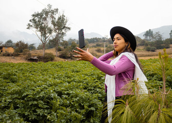 Mujer campesina con sombrero con la mano tira su celular al aire tomandose selfie,en el aire celular,movil en el aire,sierra estilo de vida