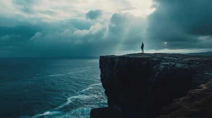 A lone figure stands on a cliff, gazing out over a stormy ocean under dramatic skies.