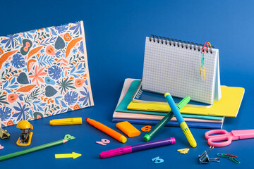 Creative composition of office supplies and notebooks on a blue background. Workplace organization concept. 