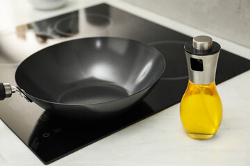 Frying pan and bottle of oil on cooktop in kitchen, closeup