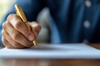 © AucArtStudio - A close-up of a hand writing with a gold pen on white paper, showcasing creativity and concentration in a professional setting.