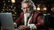 © Dalidudko - A modern-day Santa Claus works at his laptop on Christmas night.