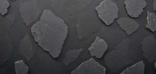 Aufkleber - a collection of dark gray, irregularly shaped rocks or stones arranged on a black background