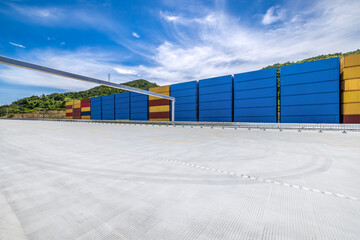 Fototapete - Stacked containers and empty asphalt road at the port
