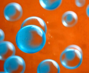 Leinwandbilder - a close-up view of numerous blue spheres floating in a light orange background, creating a sense of depth and movement