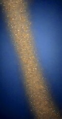 Fototapete - A diagonal line of gold glittering particles against a dark blue background