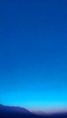 Fototapete - A starry night sky with a few distant stars and a faint mountain silhouette in the bottom right corner