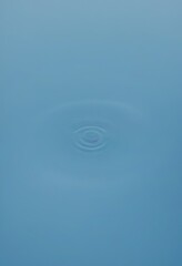 Leinwandbilder - a single, small ripple in a light blue body of water, with a darker blue background