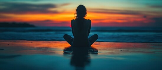 Poster - Silhouette of a woman meditating on a beach at sunset.