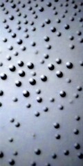 Poster - a close-up view dark, textured surface with numerous small, round, black dots arranged in a pattern