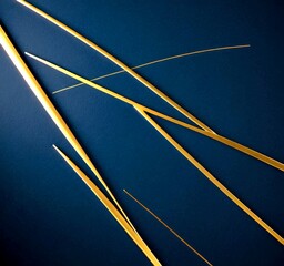 Aufkleber - a close-up view of several thin, golden-colored metal rods or wires arranged in a diagonal pattern against a dark blue background