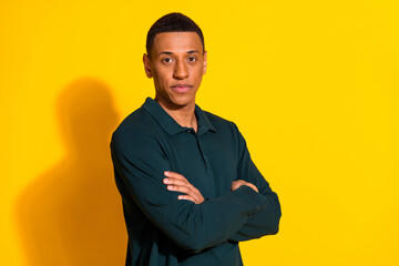 Wall Mural - Photo portrait of attractive young man crossed hands confident dressed stylish green clothes isolated on yellow color background