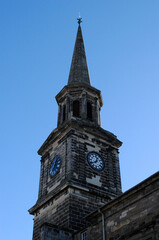 Wall Mural - Old Church with Spire and Clock seen from below against Blue Sky 