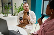 © Seventyfour - Medium shot of male podcast guest talking to female host while recording new episode holding professional microphone sitting at cafe table, copy space