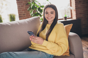 Wall Mural - Photo portrait of attractive teen woman sit couch hold device dressed yellow outfit cozy day light home interior living room