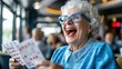 © Pinklife - An elderly woman is shown enjoying a game of bingo in a lively indoor setting, holding bingo cards, representing community, engagement, and delight.