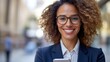© Pinklife - A joyful woman in business attire with stylish glasses checks her phone in a city street, representing professional communication and urban sophistication.