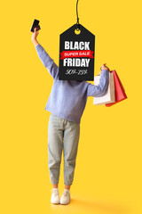 Poster - Emotional young woman with credit card, mobile phone and shopping bags on yellow background