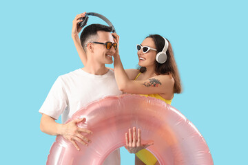 Sticker - Young couple with headphones and inflatable ring on blue background