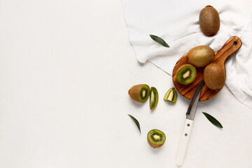 Wooden board with fresh kiwi and leaves on white background