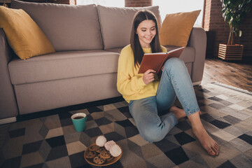 Poster - Full body photo of charming teen girl sit floor read book relax eat snacks wear yellow clothes modern interior flat indoors