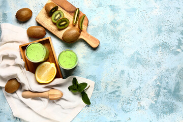 Wall Mural - Glasses of fresh kiwi smoothie with mint and lemon on light blue background