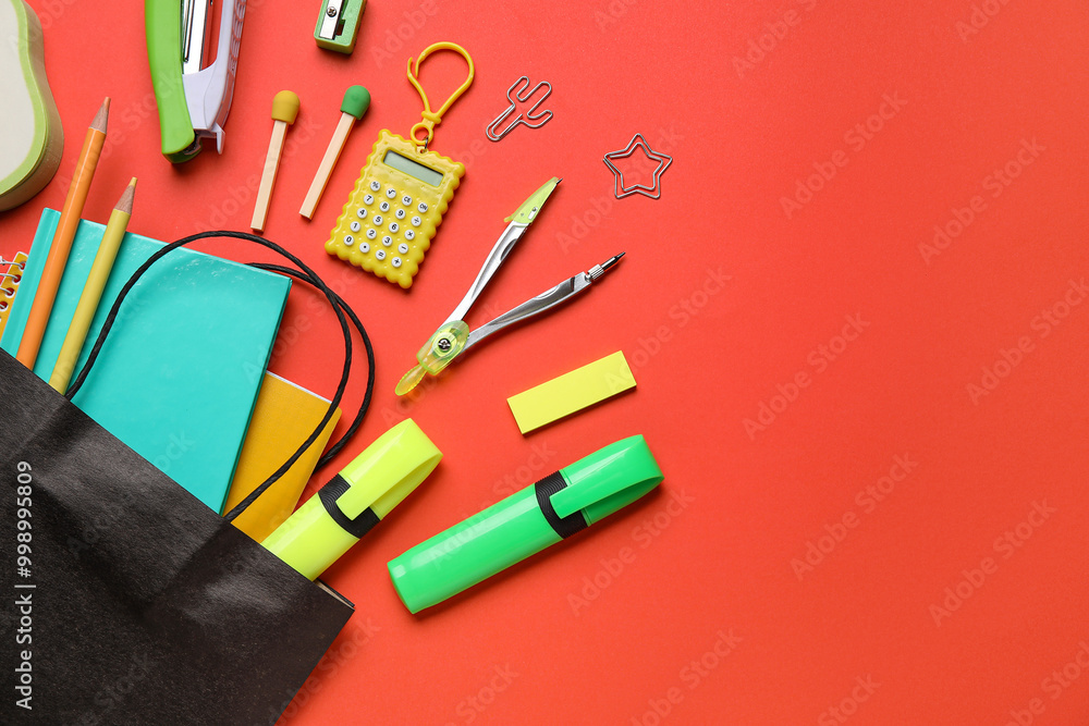 Paper bag with colorful stationery on red background