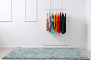 Wall Mural - Rack with colorful t-shirts near light wall