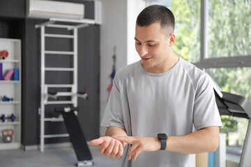 Poster - Sporty young man checking pulse in gym