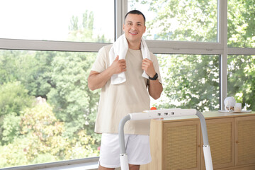 Wall Mural - Sporty young man training on treadmill at home