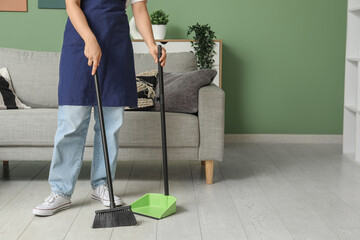 Poster - Woman sweeping floor with broom and dustpan in living room