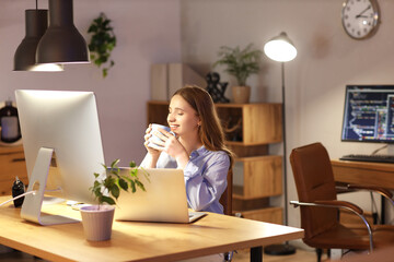 Sticker - Young businesswoman drinking coffee in office at night