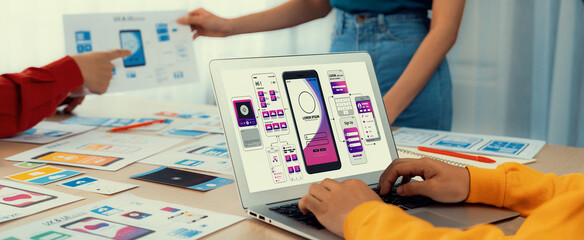 Panorama banner of startup UX developer or company employee design user interface or UI prototype for mobile application or website software with software display on laptop monitor in office. Synergic