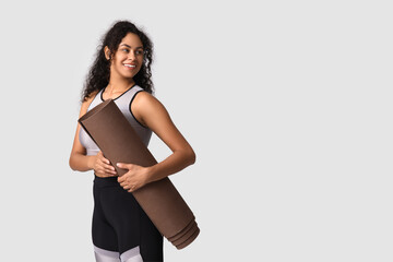 Wall Mural - Sporty young African-American woman with yoga mat on grey background