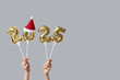 © Pixel-Shot - Female hands with figure 2025 made of foil balloons and Santa hat on white background