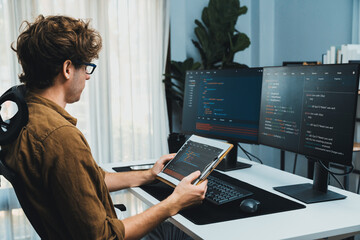 Working IT developer reading online software development information on document report surrounded by coding application screens, creating program for firmware on website at modern office. Gusher.