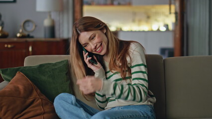 Wall Mural - Joyful woman talking mobile phone relaxing at home couch. Smiling girl gossiping